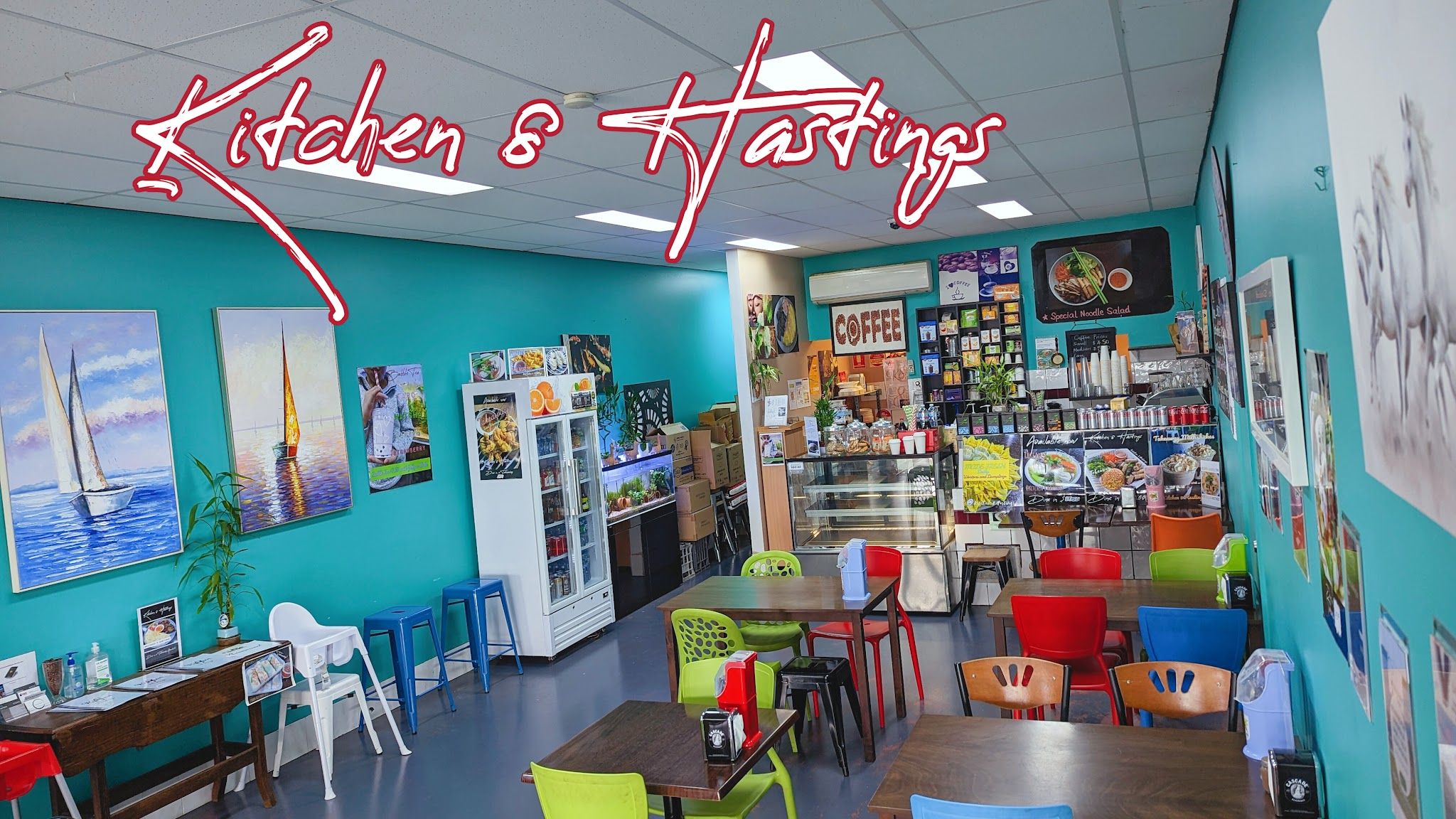 Kitchen 8 Hastings dining room — teal walls with colourful artwork and mismatched chairs
