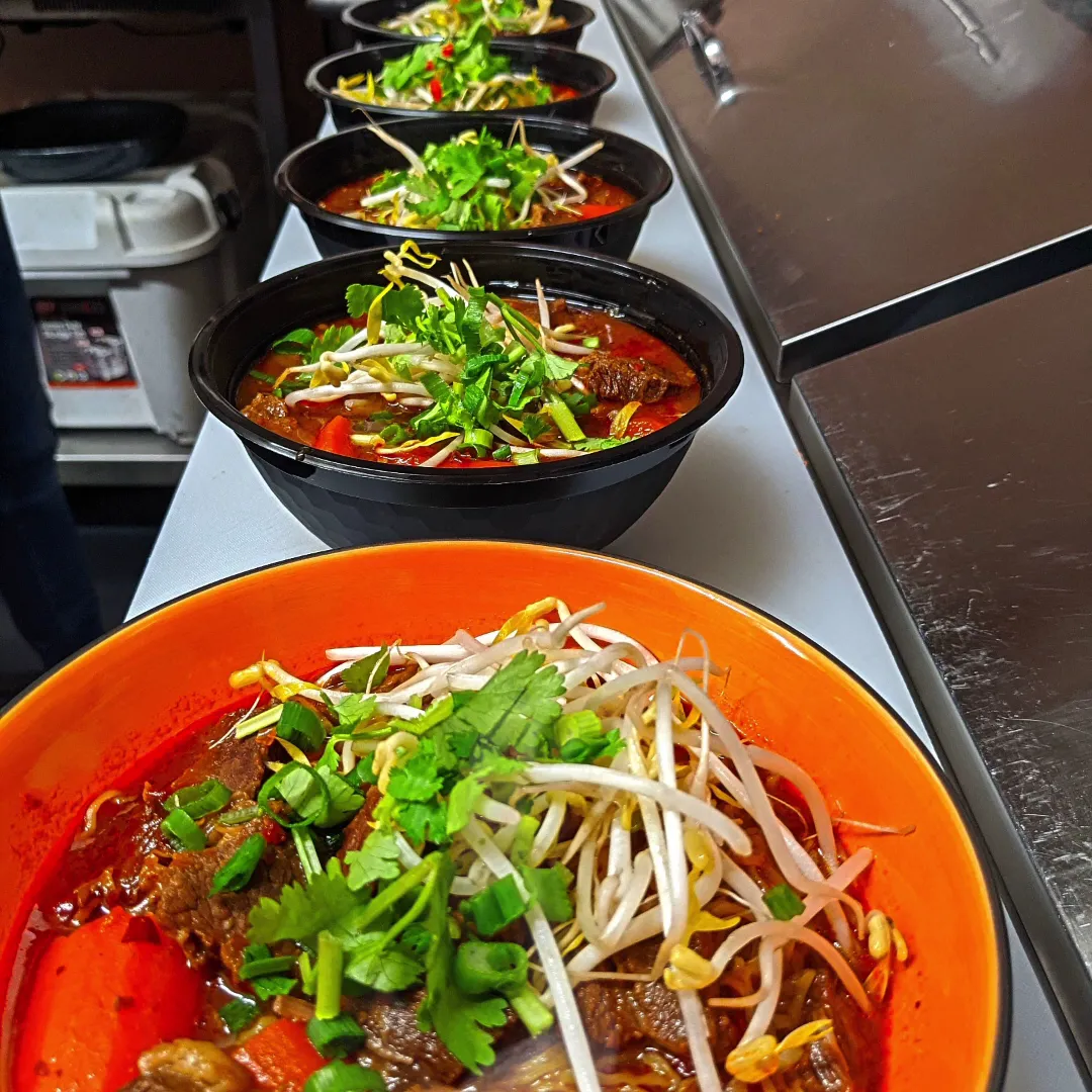 Row of Cambodian beef stew bowls on a stainless steel kitchen counter at Kitchen 8 Hastings