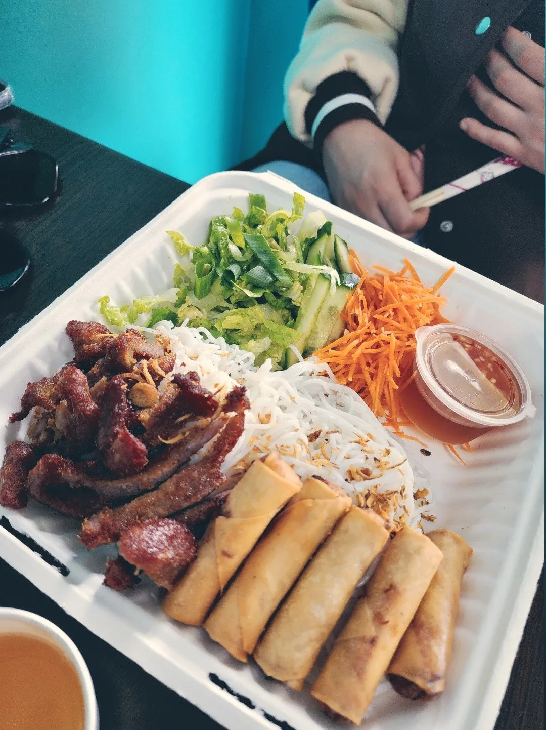 Vietnamese bun thit nuong with spring rolls, grilled pork and vermicelli on a takeaway tray